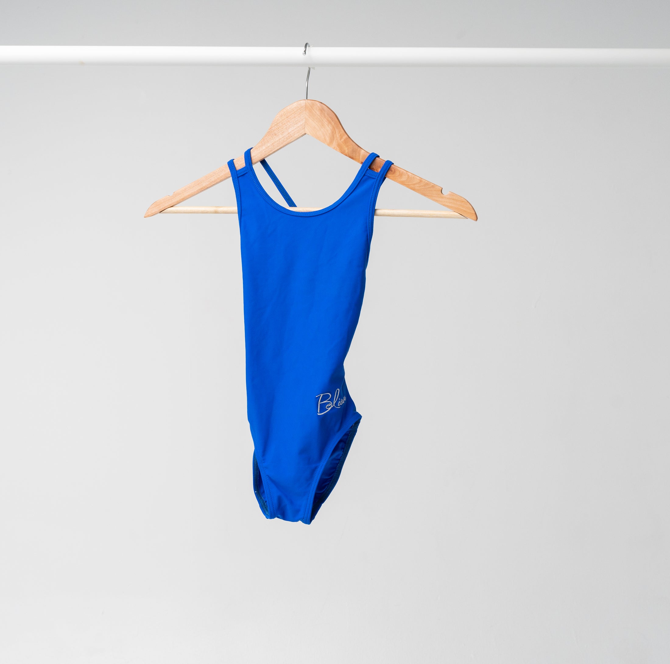 A blue leotard displayed on a wooden hanger 