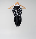 Carica l'immagine nel visualizzatore della galleria, Black and white gymnastics leotard with decorative rhinestones hanging on a wooden hange
