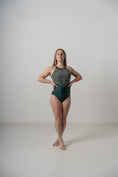 Load image into Gallery viewer, A female gymnast posing confidently in a sparkly gray and green leotard
